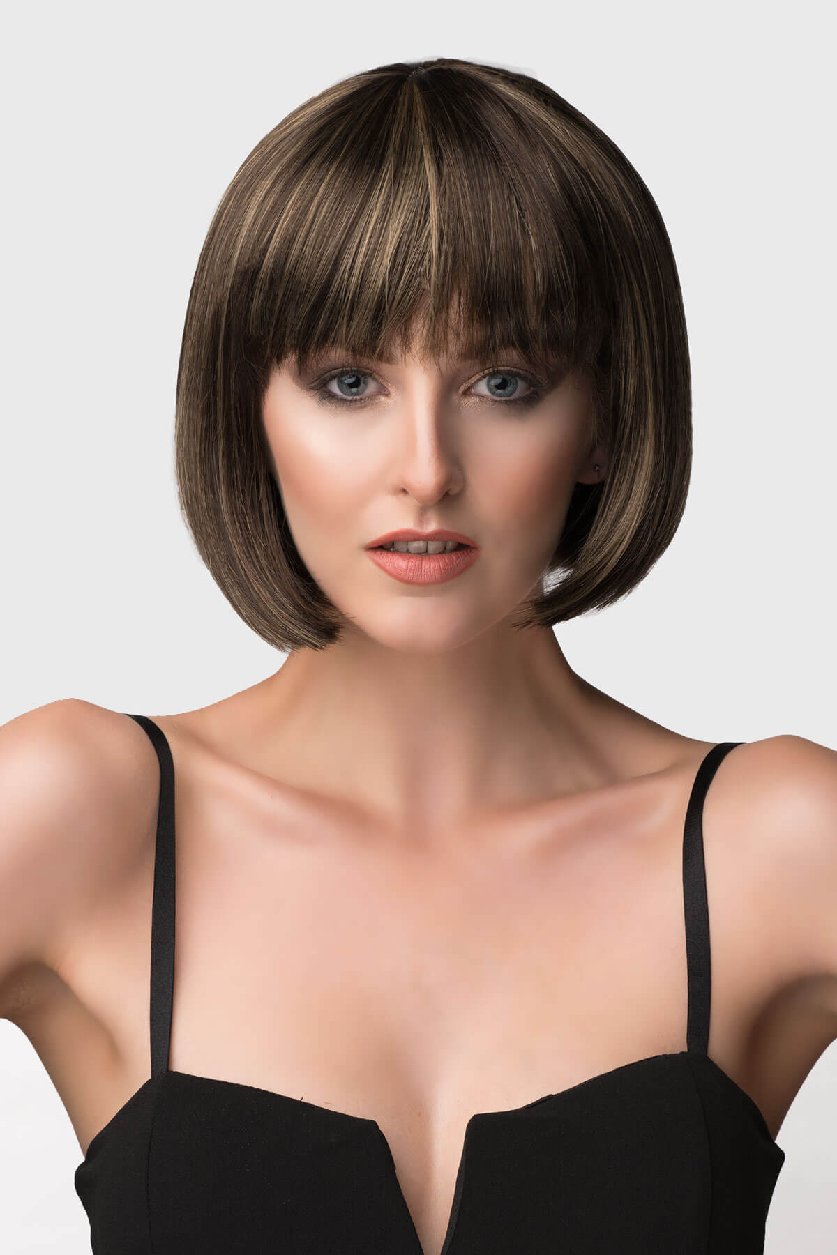 Woman with a stylish bob haircut against a plain background. Chestnut brown bob wig with blonde highlights: Lorna