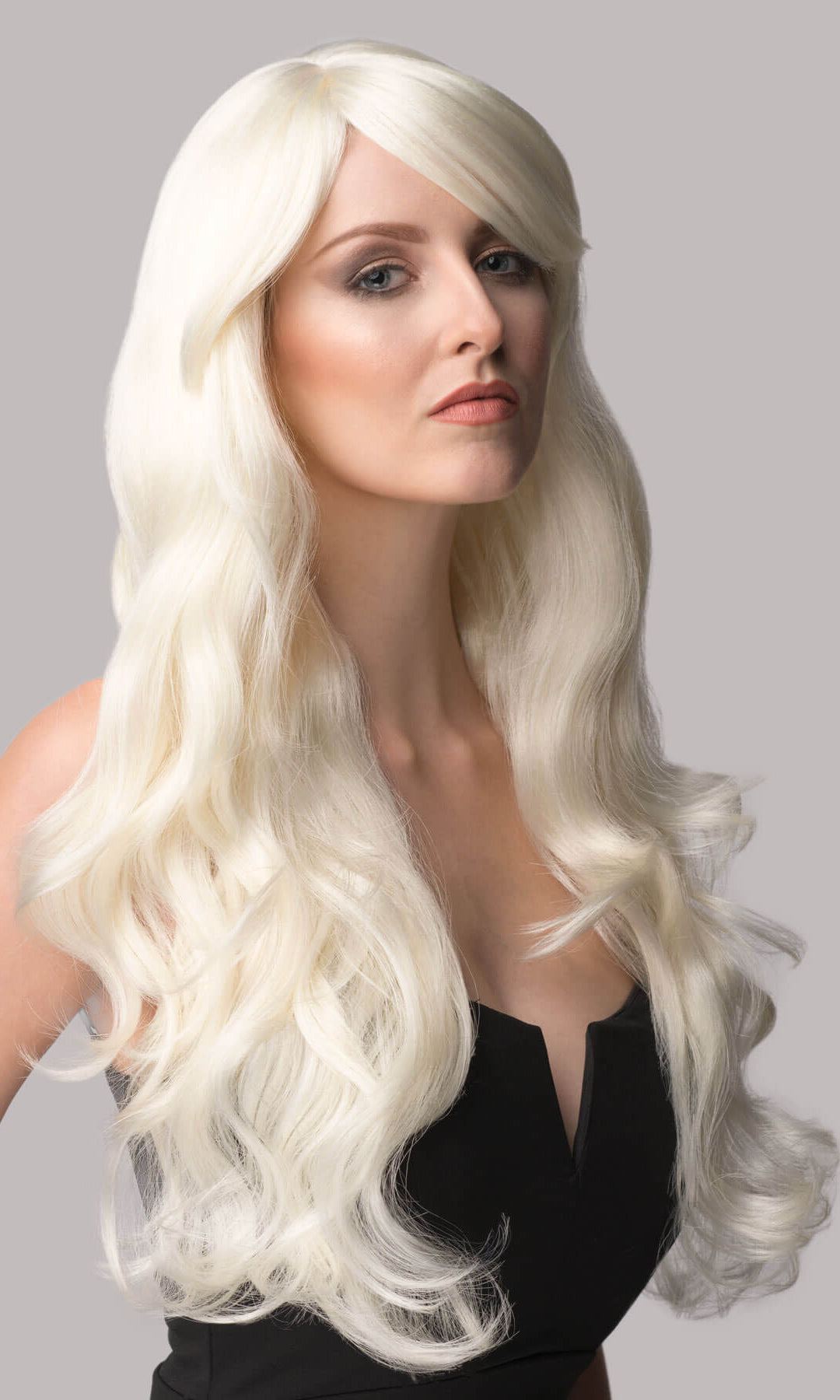 Woman wearing a long blonde wig against a gray background. Long Platinum Blonde Wig (White Wig) Loose Curls: Andreana