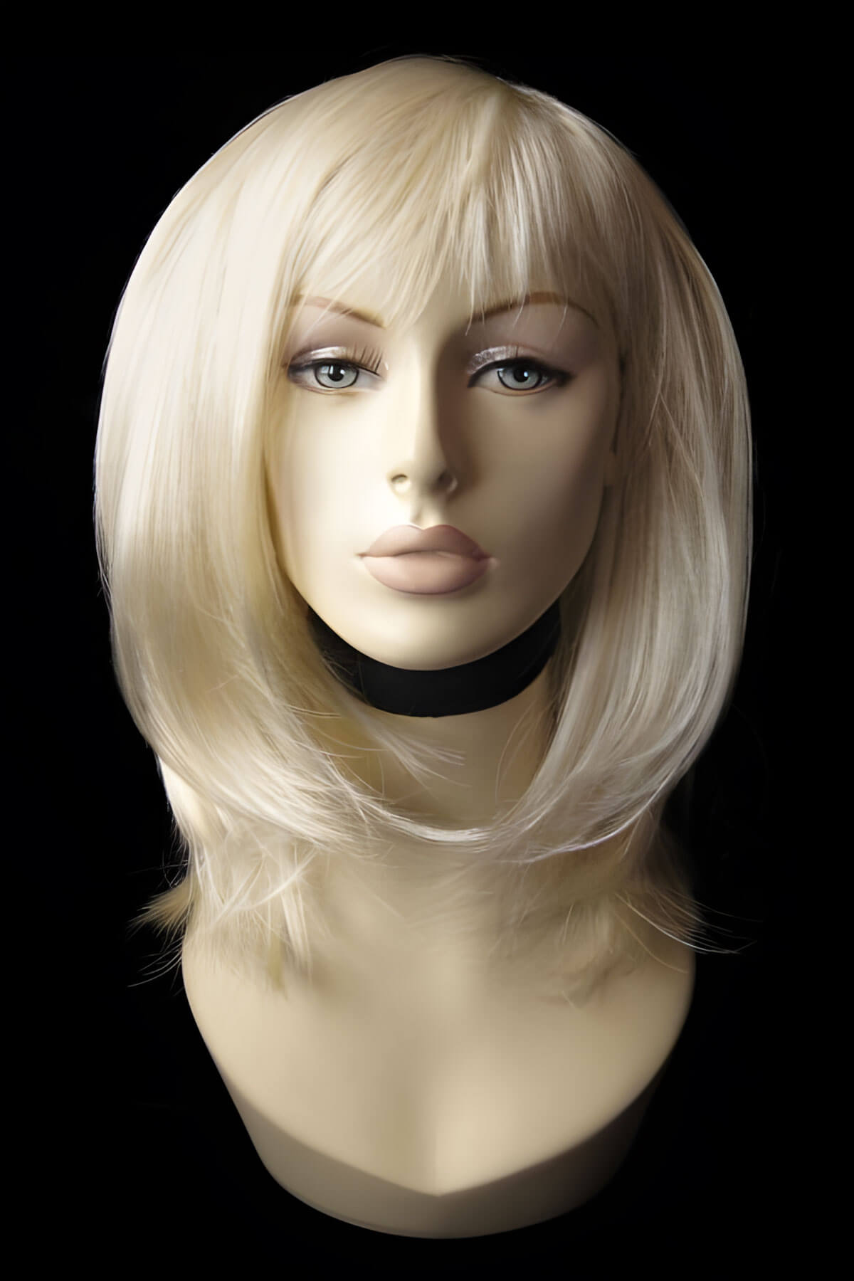 Blonde wig on a mannequin head against a black background. Blonde mid-length wig, face frame, layered style: Lilly champagne blonde 613