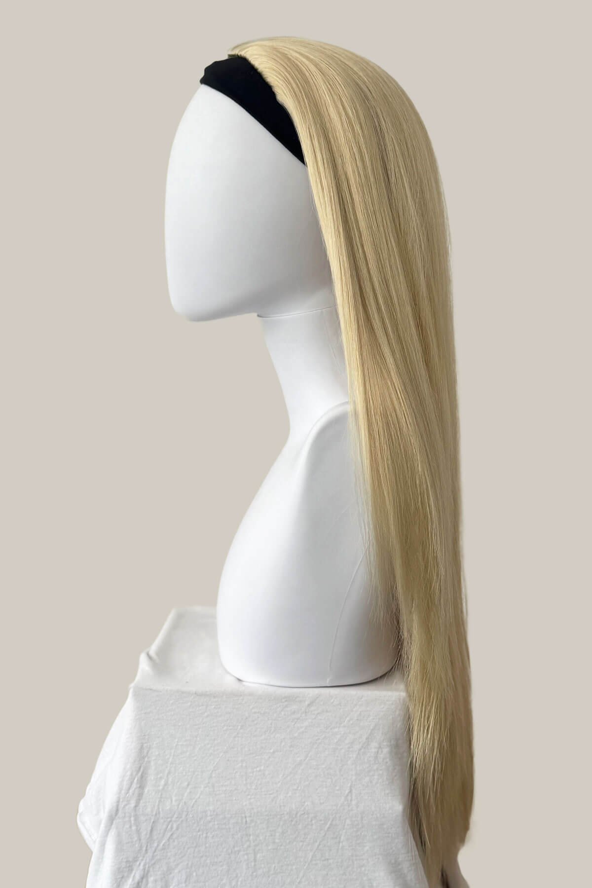 Mannequin head with a long blonde wig on a plain background. Straight blonde half wig hairpiece (3/4 wig): Tabitha creamy blonde 613