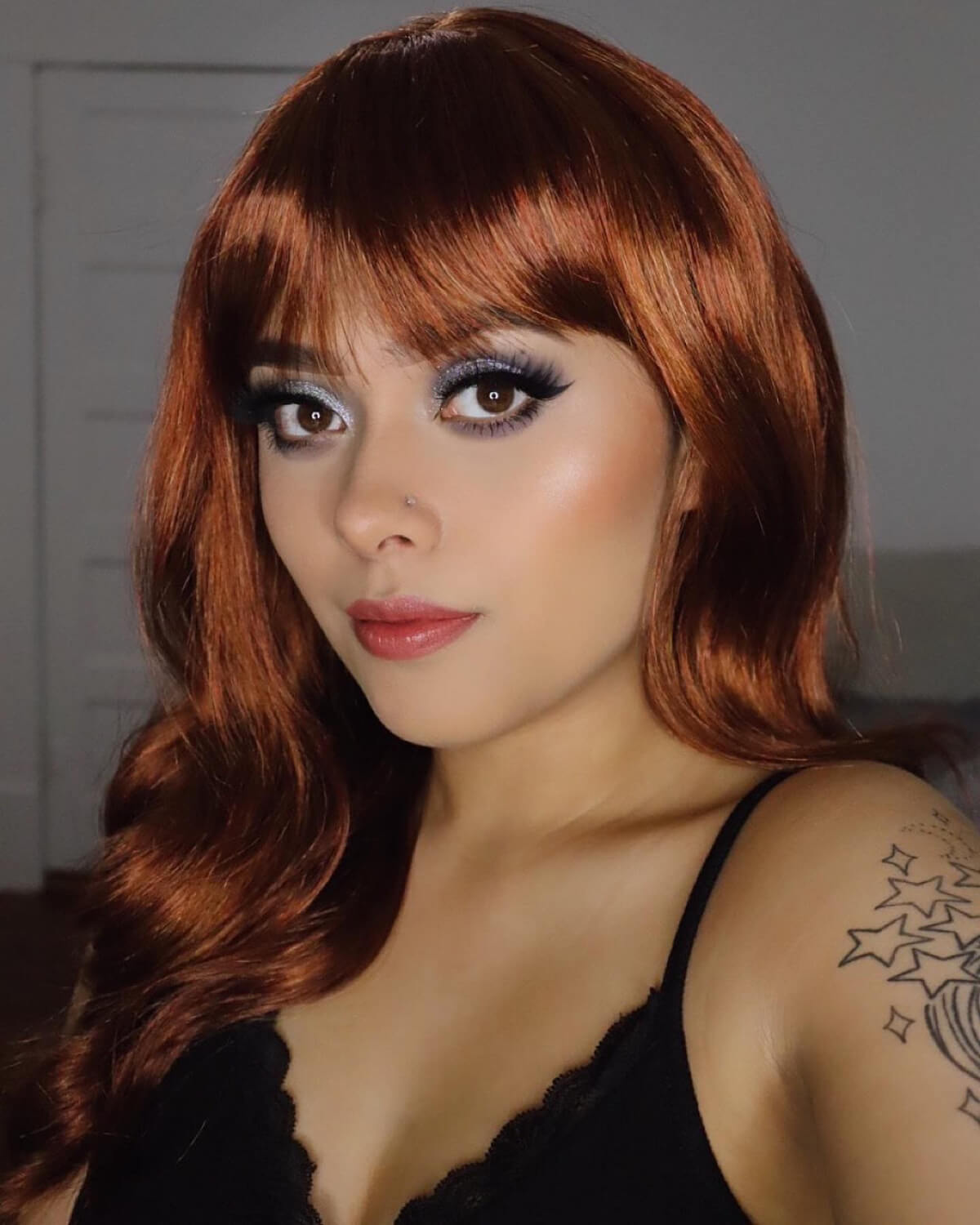 Woman with red hair and makeup wearing a black top. Red, auburn & blonde wig with long cascading waves: Floriana