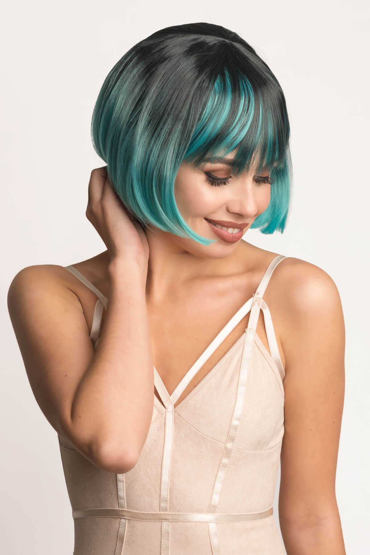 Woman with a stylish haircut featuring black and teal hair on a plain background. Bob wig, black ombre blending to turquoise blue: Amara