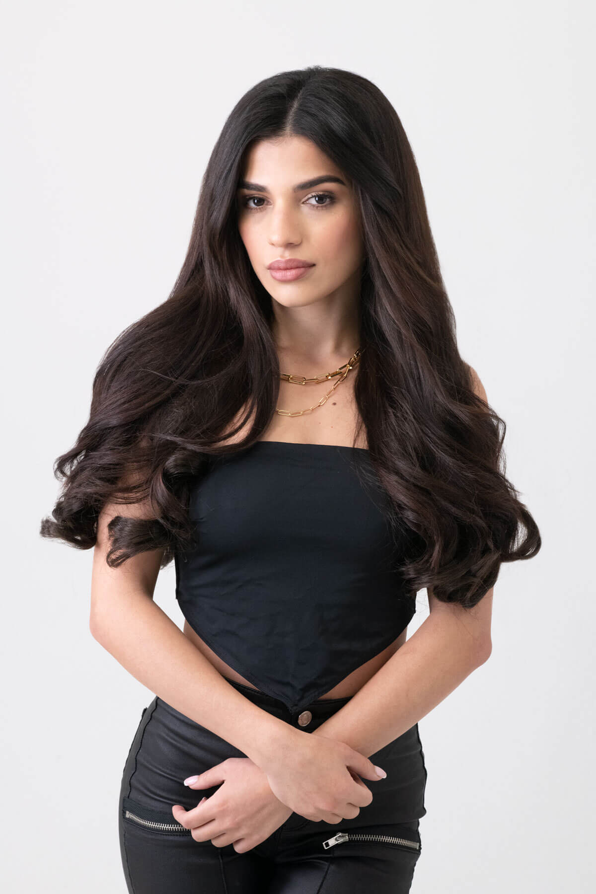 Woman with long dark hair wearing a black outfit on a white background. 5 piece synthetic hair extension set, 18 inches long, 260g