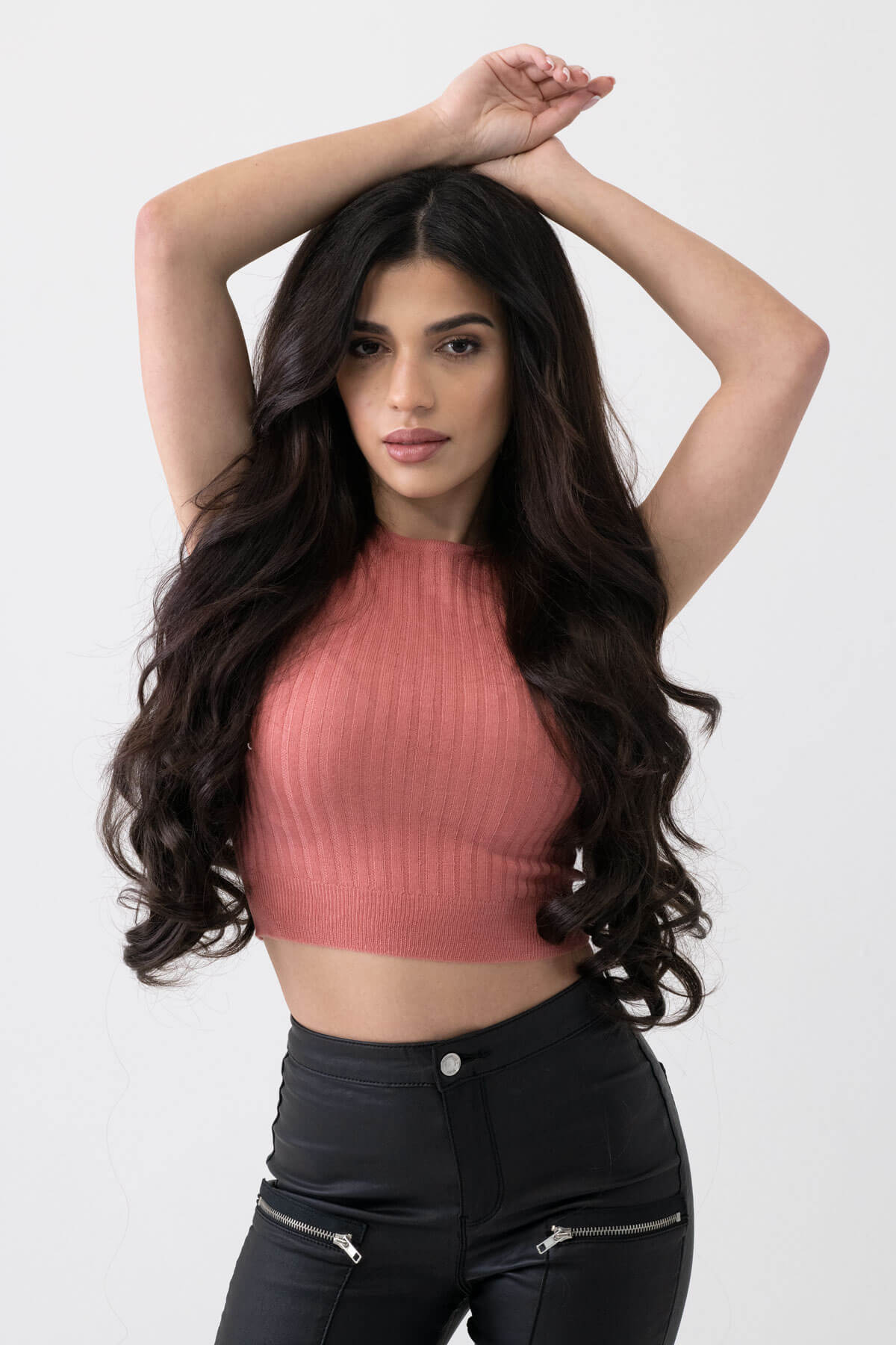 Woman wearing a pink ribbed top and black pants against a white background. synthetic hair extension set, 5 piece, 22 inches long, 300g