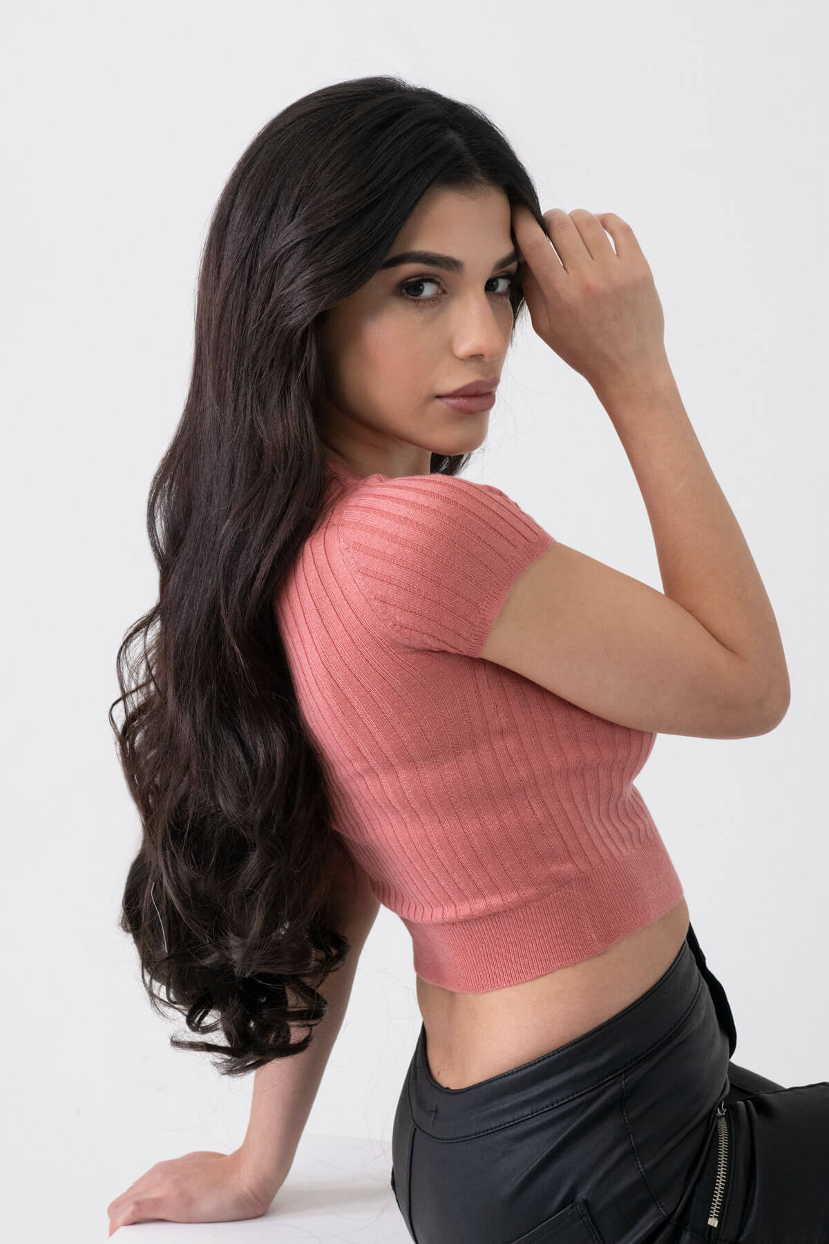 Woman wearing a pink ribbed top and black pants against a white background. synthetic hair extension set, 5 piece, 22 inches long, 300g