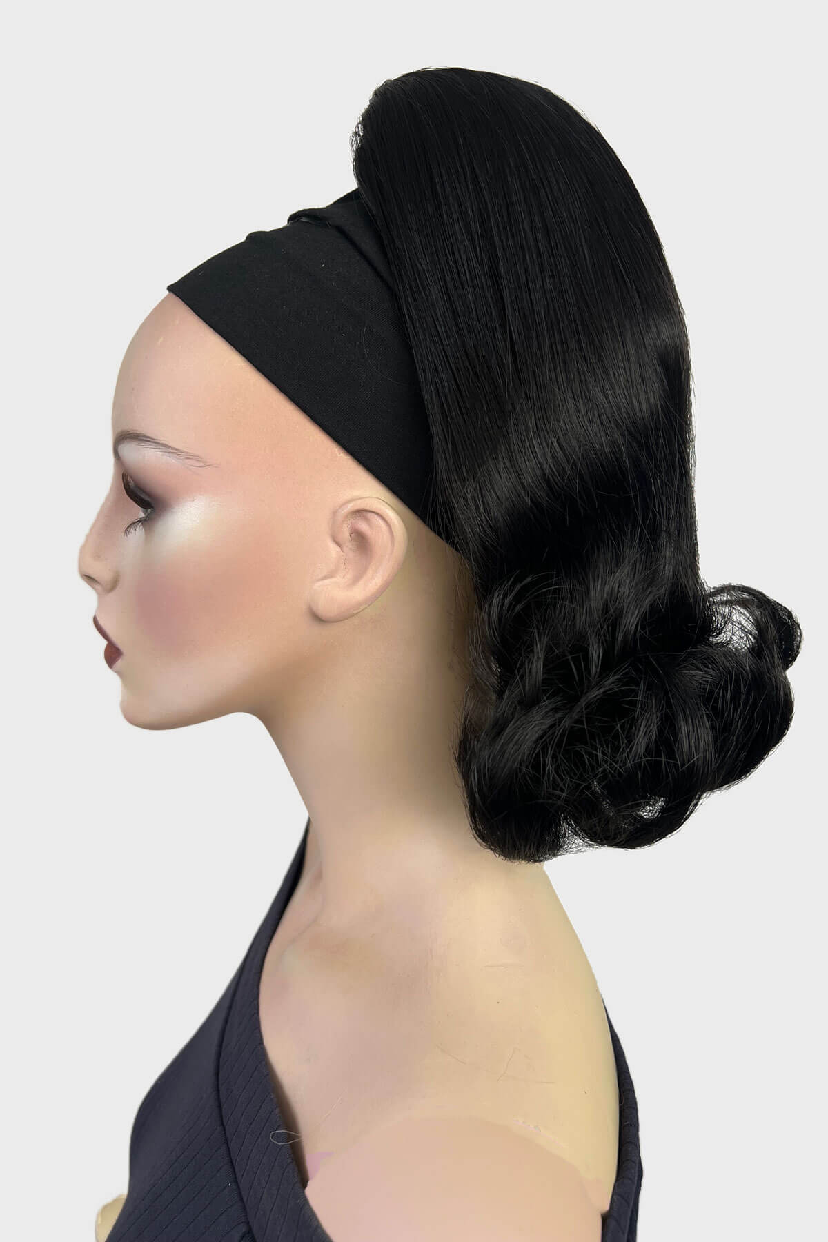Mannequin head with black hair styled in a bun against a white background. Ponytail hairpiece, shoulder length with flick/flip, retro 1960s style: Ariana black 1B
