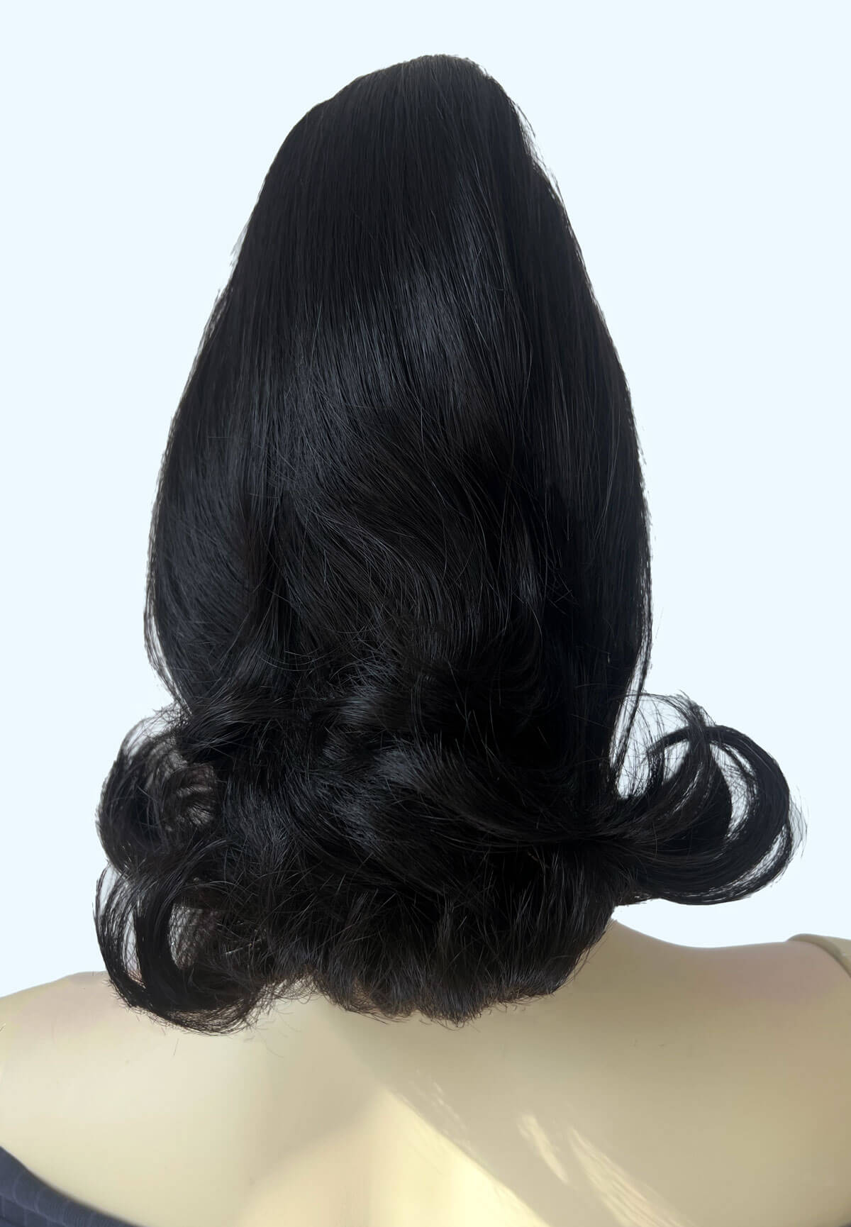 Black hairpiece styled in an updo on a mannequin head against a light gray background. Ponytail hairpiece, shoulder length with flick/flip, retro 1960s style: Ariana black 1B
