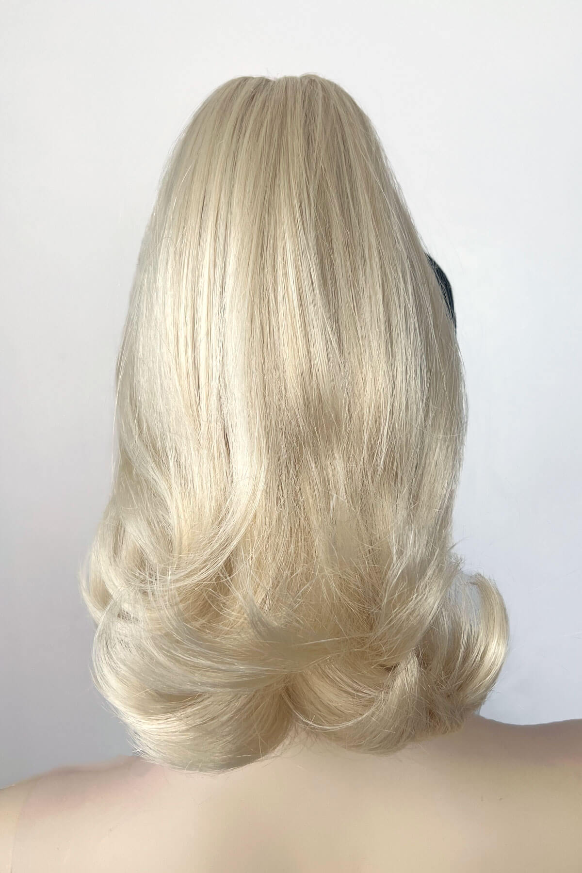 Blonde wig on a white background. Ponytail hairpiece, shoulder length with flick/flip, retro 1960s style: Ariana creamy blonde 613