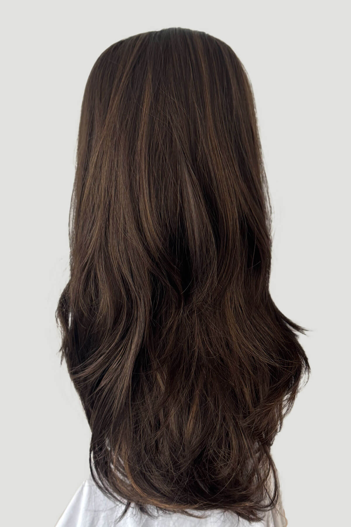 Long, wavy brown hair on a white background. 1960s style hair, high crown long straight and layered half wig: Juliette brown with blonde highlights 8H27