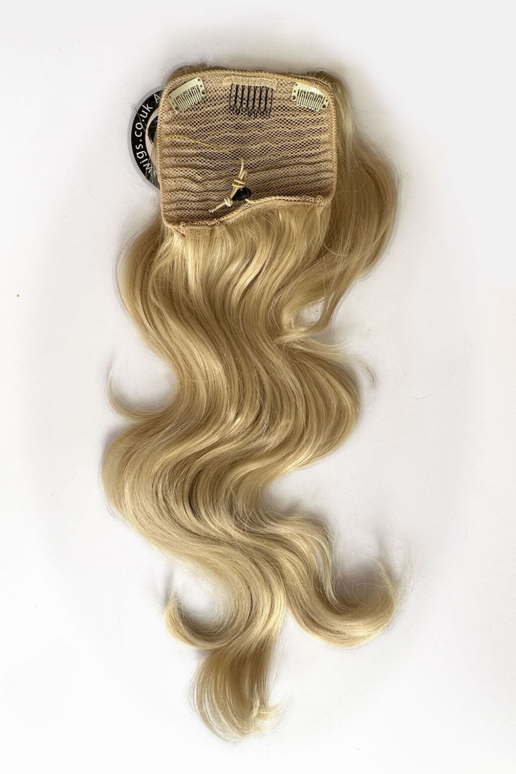 Blonde hair extension with a clip on a white background. Double volume hairpiece extension: Naomi blonde 613