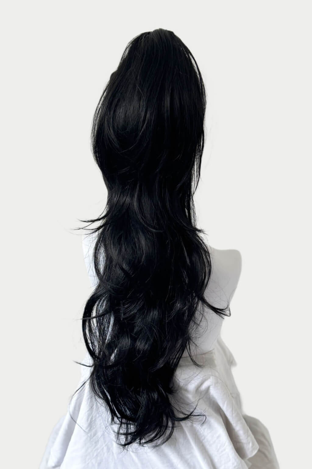 Black hair wrap on a mannequin head against a white background. Clip-in ponytail hairpiece extension: Olivia black 1B