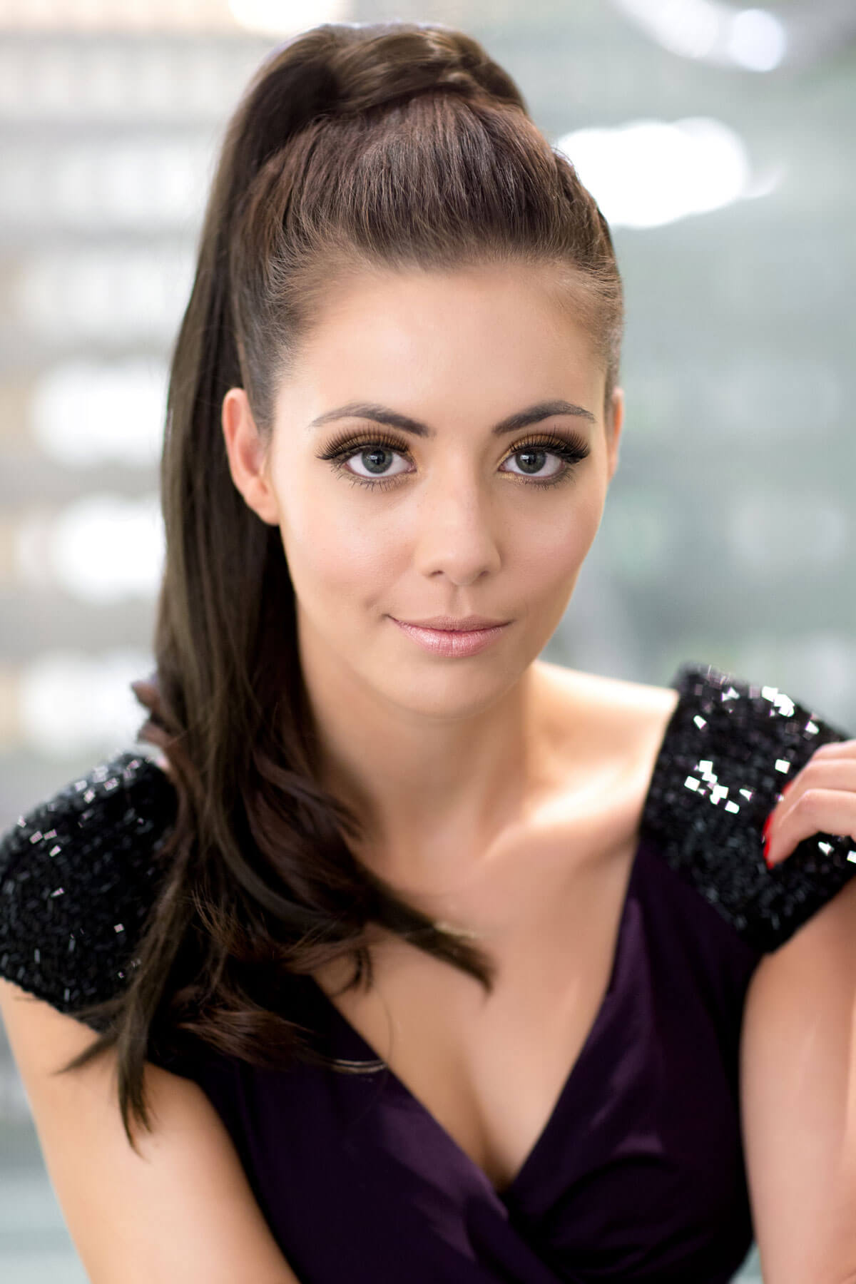 Woman with a stylish hairdo wearing a dark purple dress with sequin shoulders. Long sleek ponytail extension with gentle, layered waves: Mali chestnut brown 8