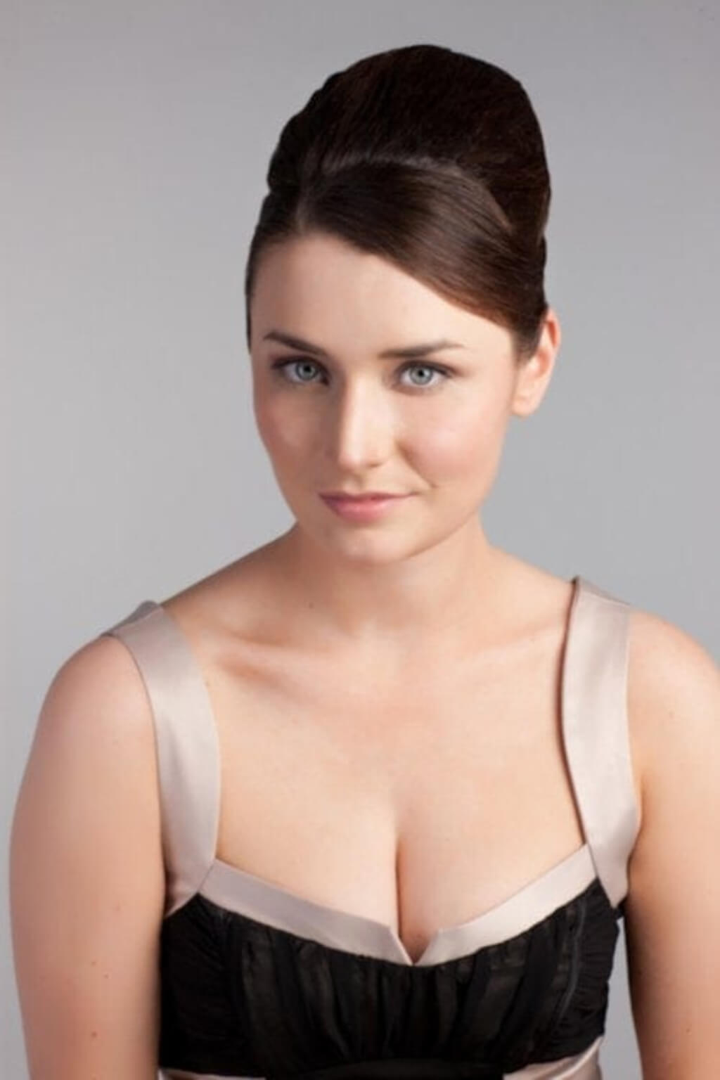 A woman with her hair styled in a beehive, wearing a black bustier-style top with beige satin straps and trim. Height Booster Hairpiece Volume and Height Booster Hairpiece, chestnut brown 8