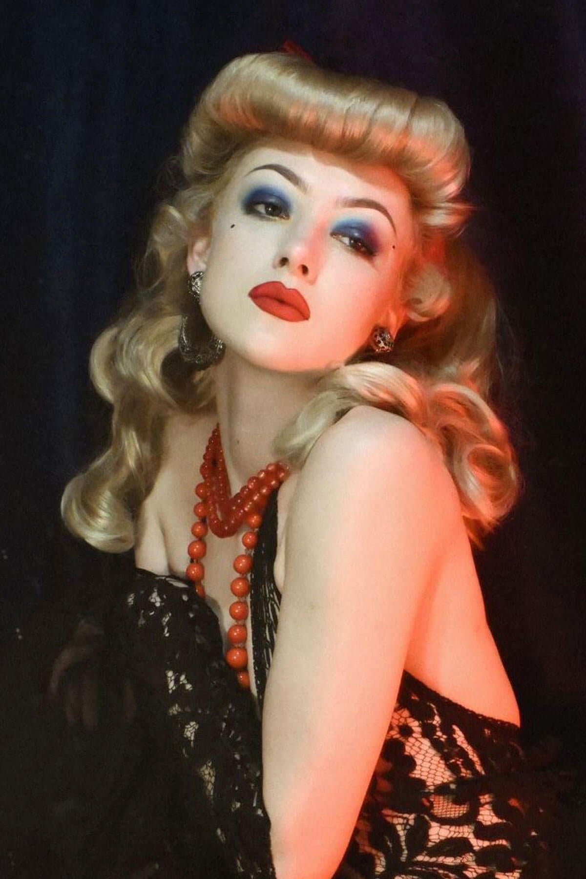 Person with dramatic makeup and a black lace top against a dark background. Bumper bangs pack - vintage 40s 50s fringe roll: Lena blonde 24H613