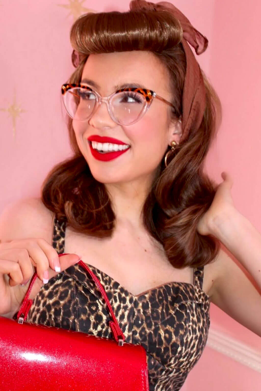 Woman with vintage hairstyle and makeup, wearing a leopard print top and red handbag against a pink background. Bumper bangs pack - vintage 40s 50s fringe roll: Lena brown 12