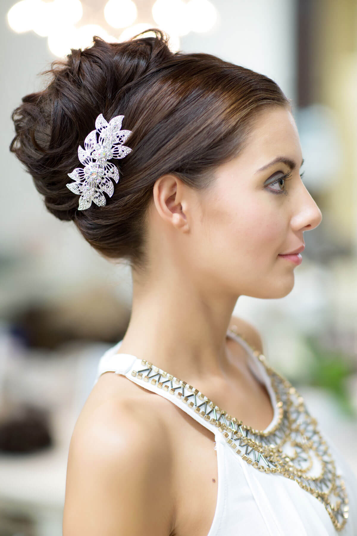 Woman with elegant updo hairstyle and decorative hairpiece, wearing a white top. Clip in hairpiece, ponytail, short, flexihair: Leela chestnut brown 8