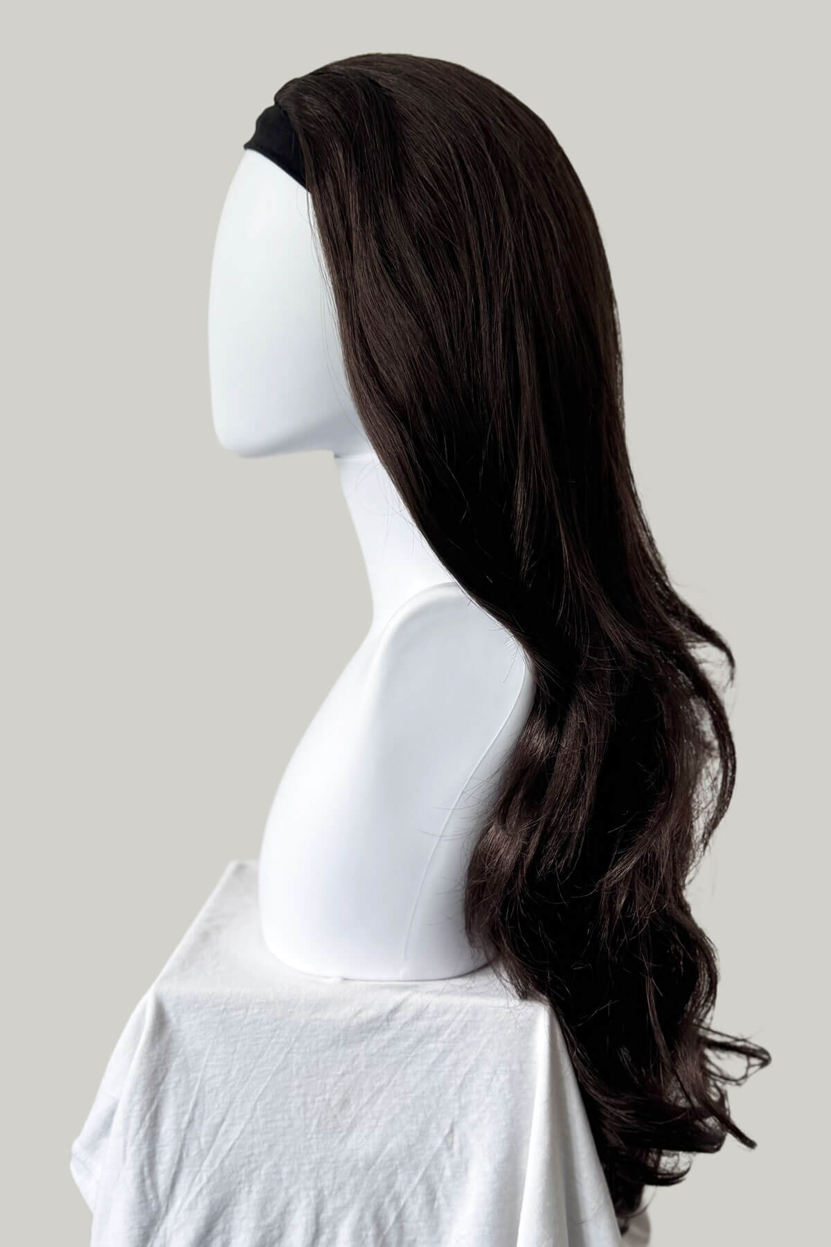 Dark brown wig on a mannequin head against a plain background. Brown half wig hairpiece, full, long with gentle waves: Taya dark chocolate brown 6