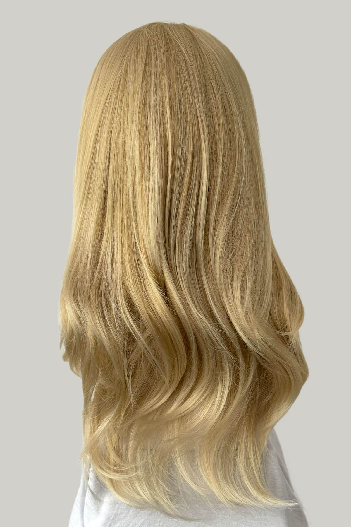 Blonde wig on a mannequin head against a plain background. Straight blonde half wig hairpiece (3/4 wig), layered: Autumn light ash blonde 24BT613