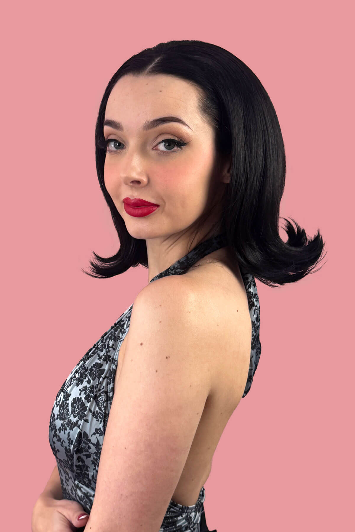 Woman with styled hair and red lipstick against a pink background. Dark brown 4