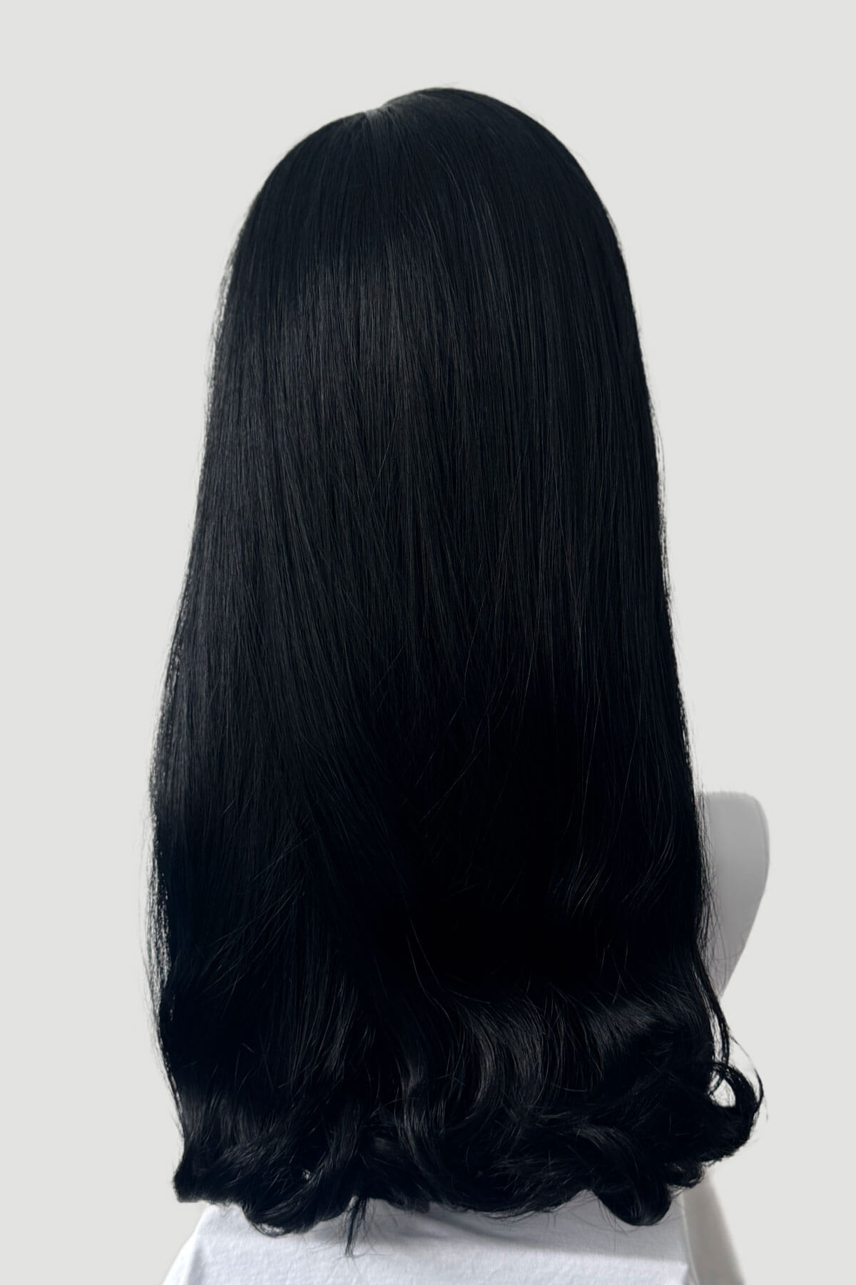 Black wig on a mannequin head against a plain background. 1960s Retro high crown, half wig hairpiece, long with hair flip: Priscilla jet black 1