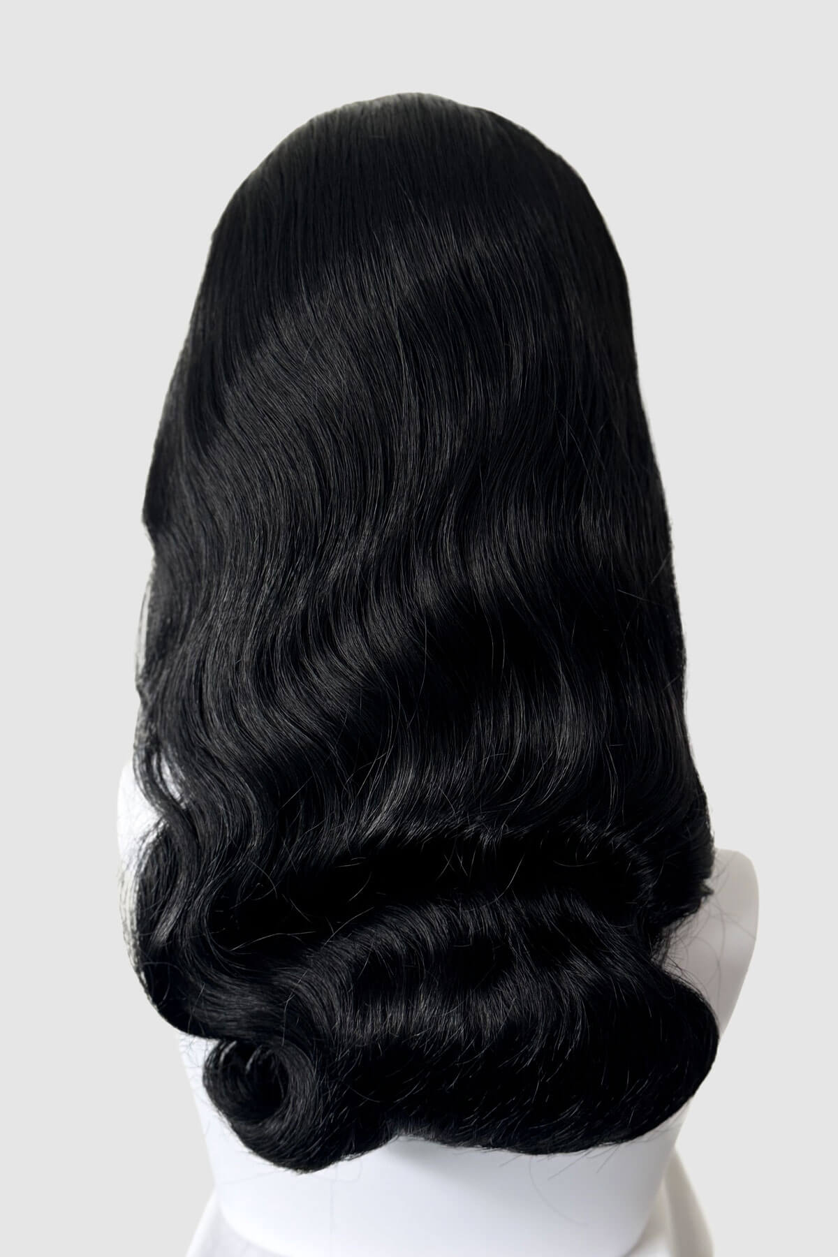 Black wig on a white mannequin head against a white background. 1950s style half wig hairpiece with beautiful waves: Morgana black 1b
