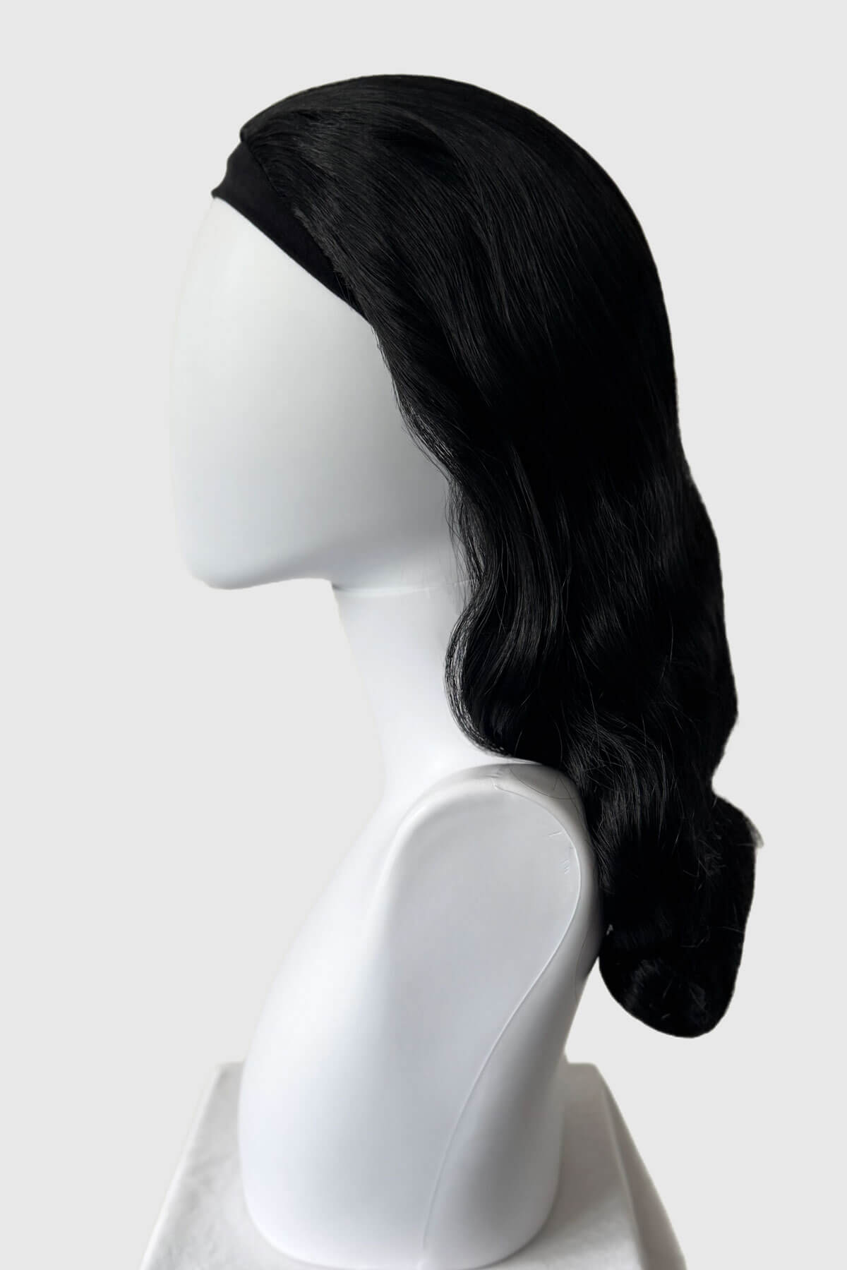 Black wig on a white mannequin head against a white background. 1950s style half wig hairpiece with beautiful waves: Morgana jet black 1