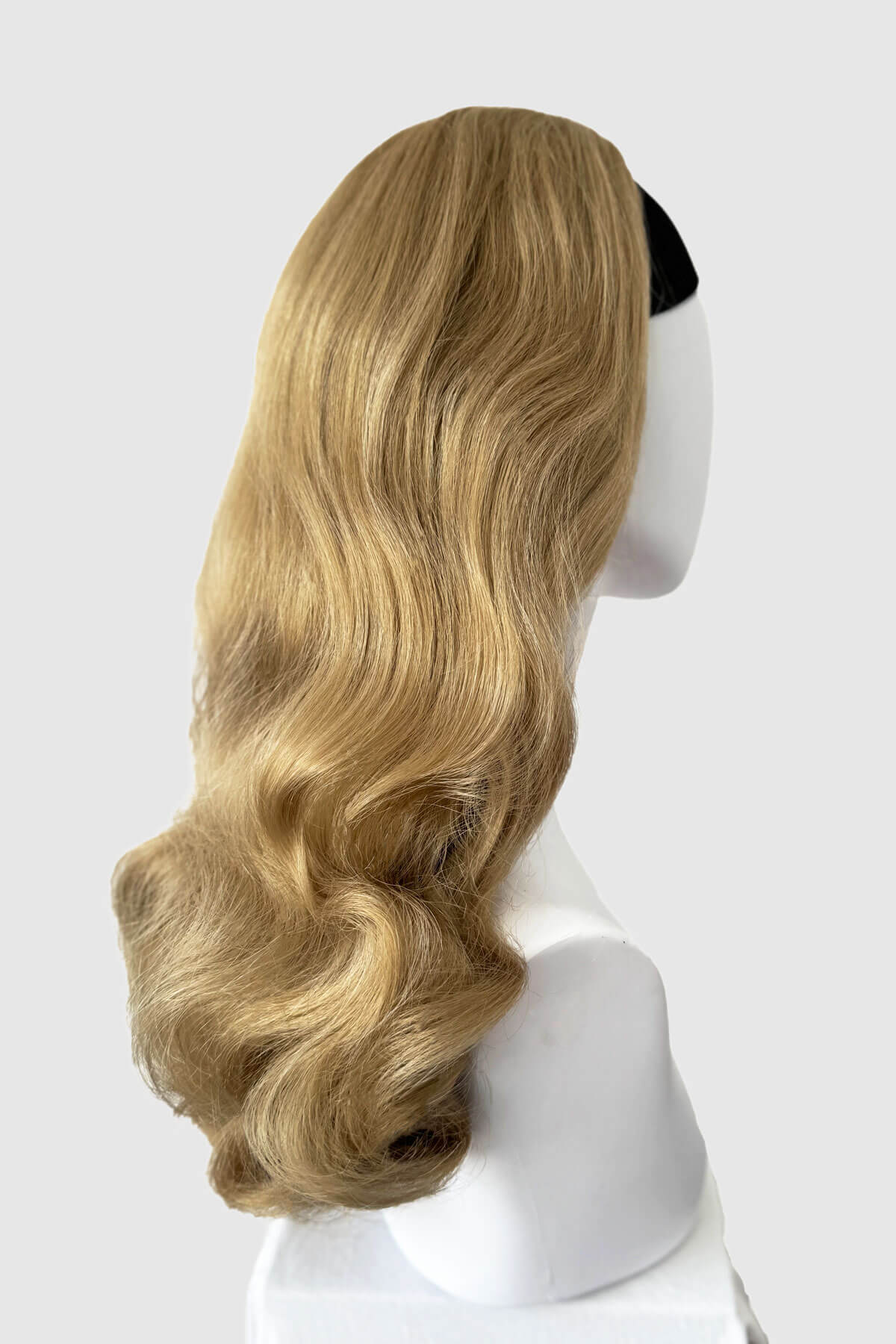 Blonde wig on a mannequin head against a white background. 1950s style half wig hairpiece with beautiful waves: Morgana blonde 24H613