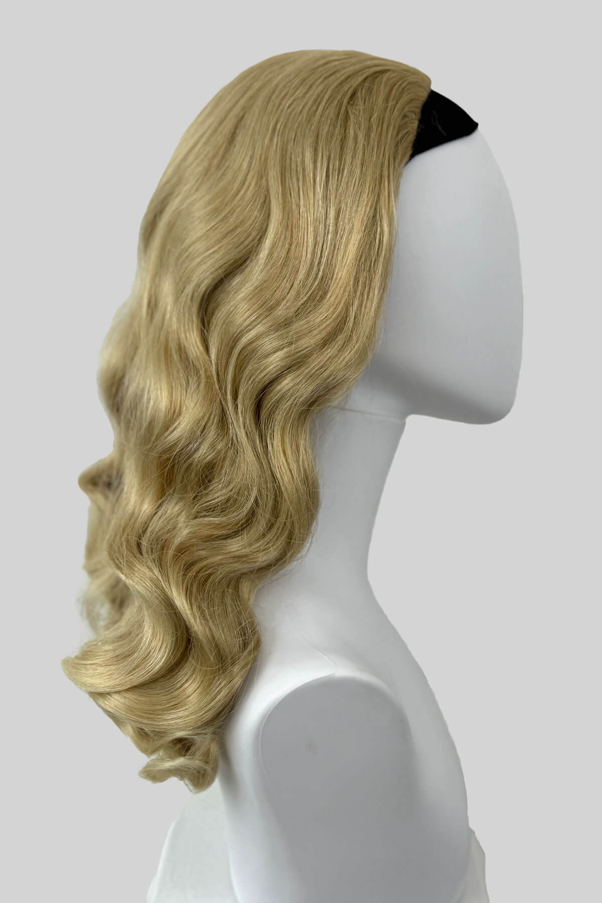 Blonde wig on a mannequin head against a white background. 1950s style half wig hairpiece with beautiful waves: Morgana blonde 613T24