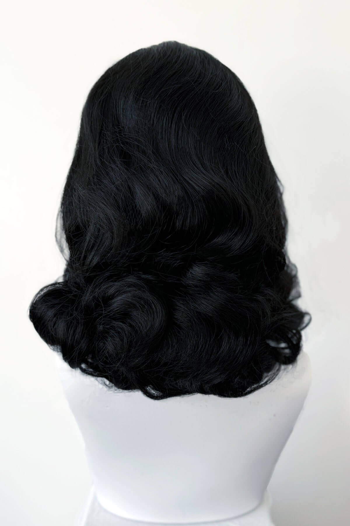 Black wig on a white mannequin head against a white background. 1950s style shoulder length half wig hairpiece with beautiful vintage waves: Onyx colour black 1B