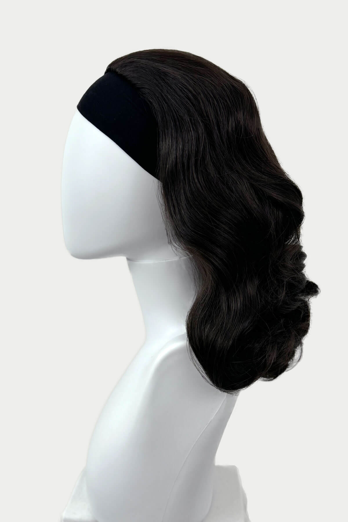 Dark brown wig on a mannequin head against a white background viewed from the side. 1950s style shoulder length half wig hairpiece with beautiful vintage waves: Onyx dark brown 4