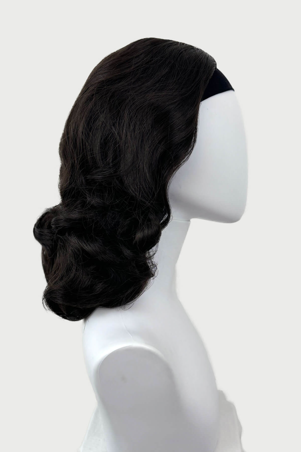 Dark brown wig on a mannequin head against a white background viewed from the side. 1950s style shoulder length half wig hairpiece with beautiful vintage waves: Onyx dark brown 4