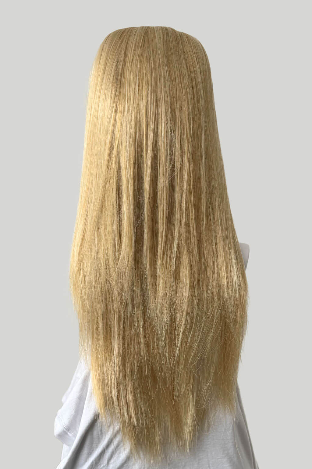 Blonde wig on a mannequin head against a plain background. 1960s style hair, high crown long straight half wig: Andrea blonde 24B613
