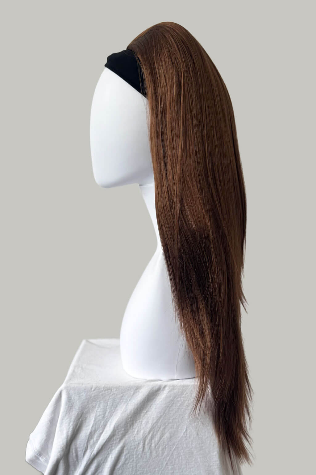 Auburn hair extension on a mannequin head against a plain background. 1960s style hair, high crown long straight half wig: Andrea auburn 30