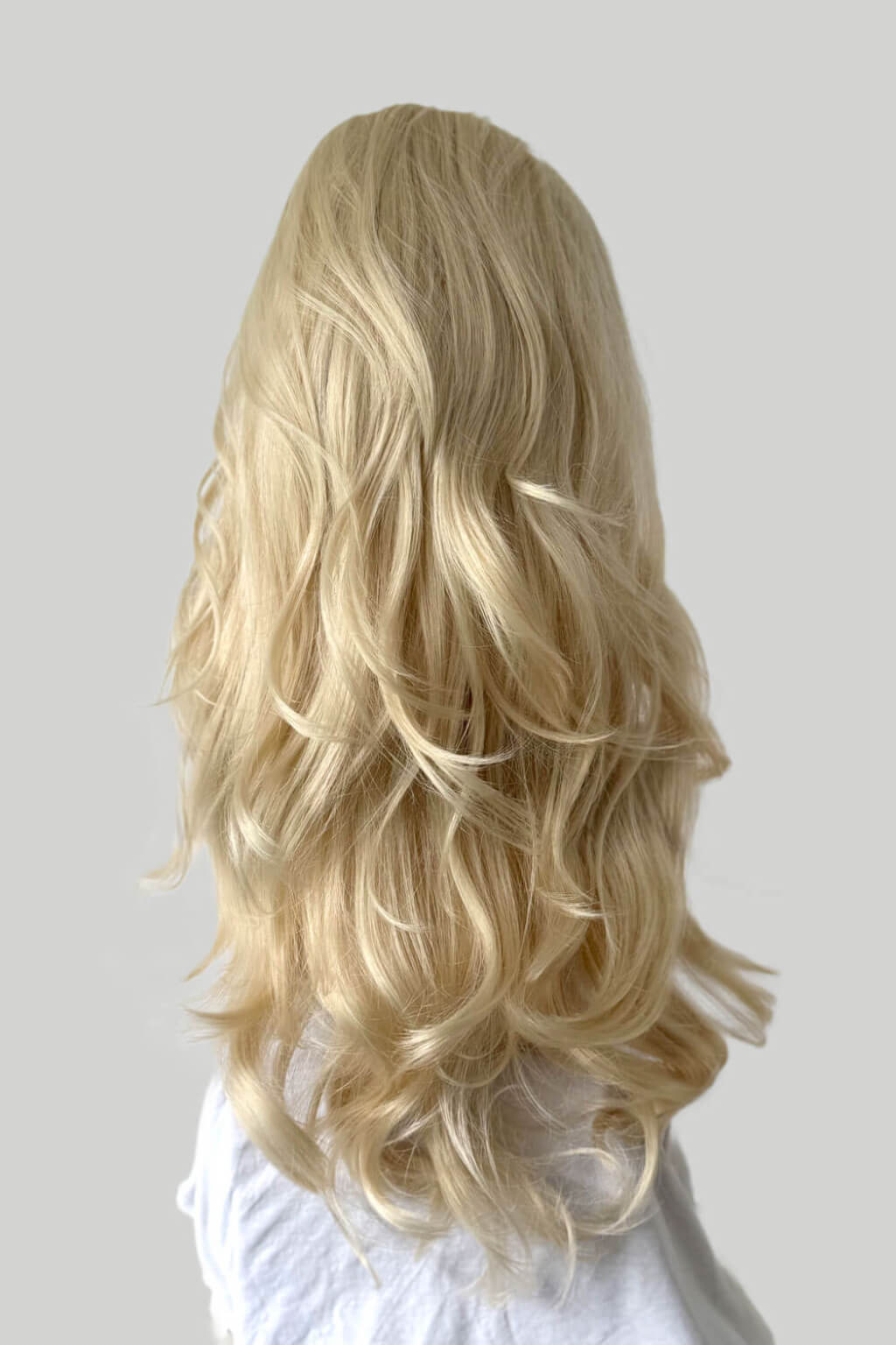 Blonde wig on a mannequin head against a plain background. High crown long, wavy half wig and volume ring: Bardot blonde 613