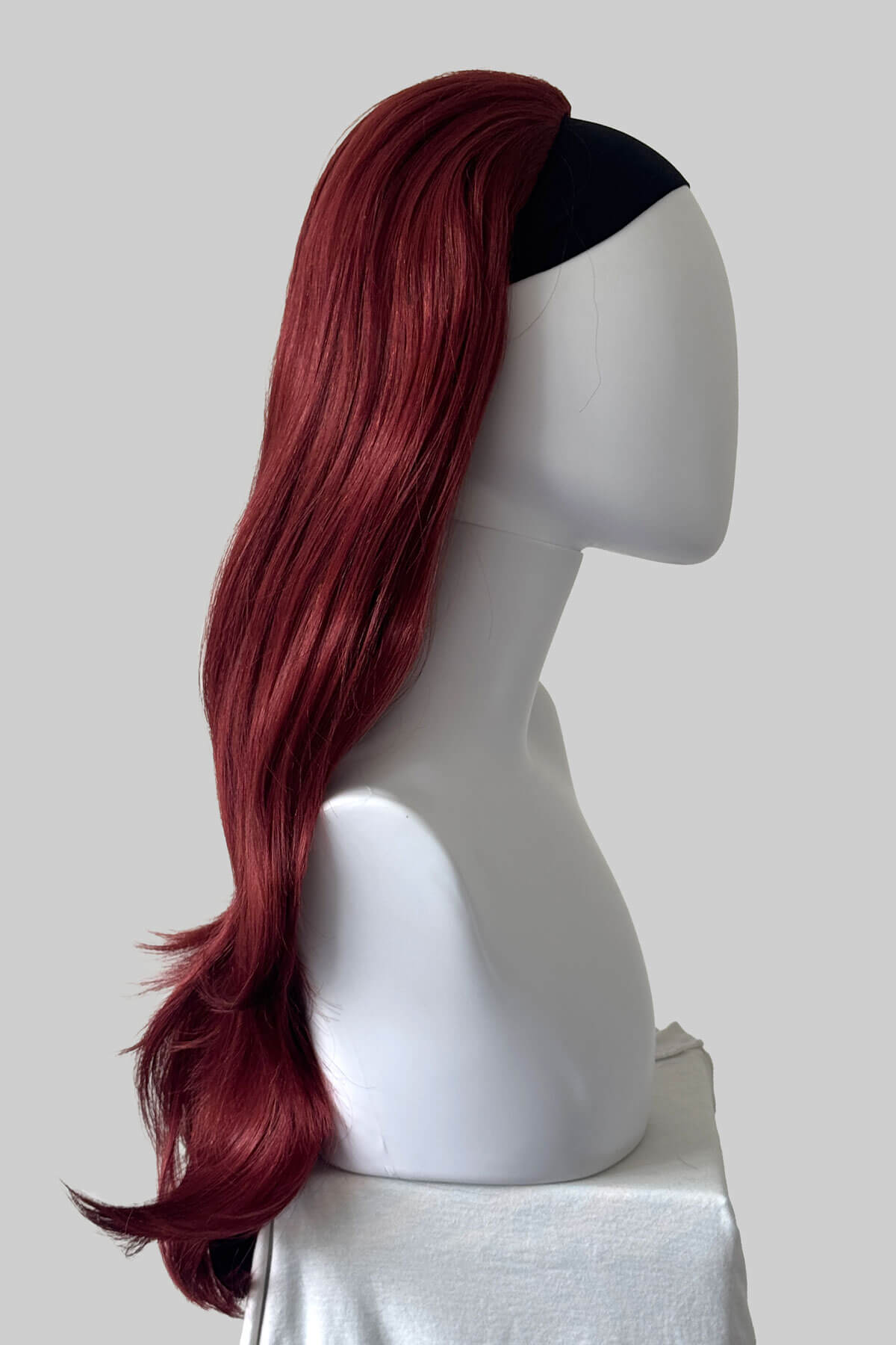 A long, wavy half wig in red displayed on a white mannequin head against a light grey background. Claudia - Volume Boosting Long Gentle Bouncy Layered Half wig copper and dark cherry red 350/39