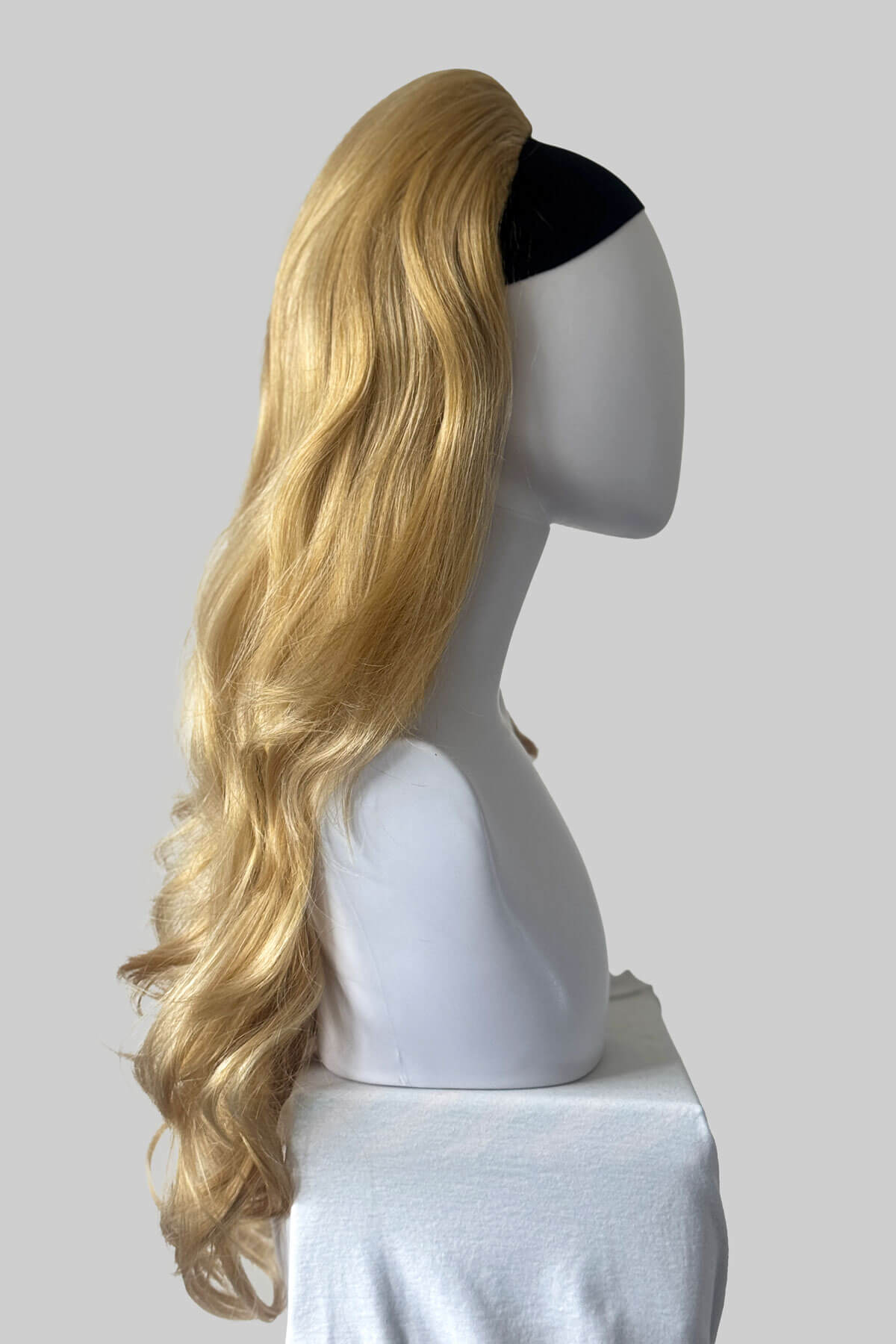 A long blonde wavy wig with a black underband, displayed on a white mannequin head against a solid gray background. Corrine - Bouncy Blowout style with Volume Booster Half Wig warm blonde 24BH613