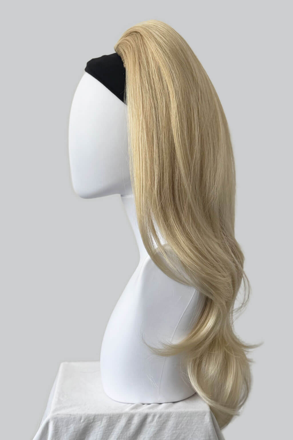 Blonde wig on a mannequin head against a plain background. 1960s style hair, high crown long straight and layered half wig: Juliette blonde 24BT613