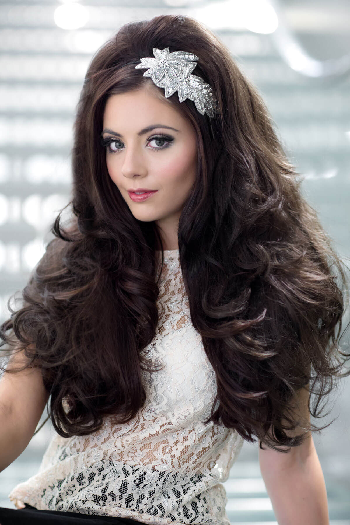 Woman with long, wavy hair wearing a decorative headband against a blurred indoor background. Volume boosting 3/4 hairpiece, long, wavy, heat styeable: Gisele chestnut brown 8