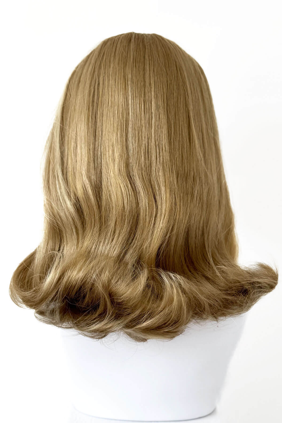 Blonde wig on a mannequin head against a white background. 1960s half wig hairpiece, flicked, hair flip: Philippa blonde 24H613