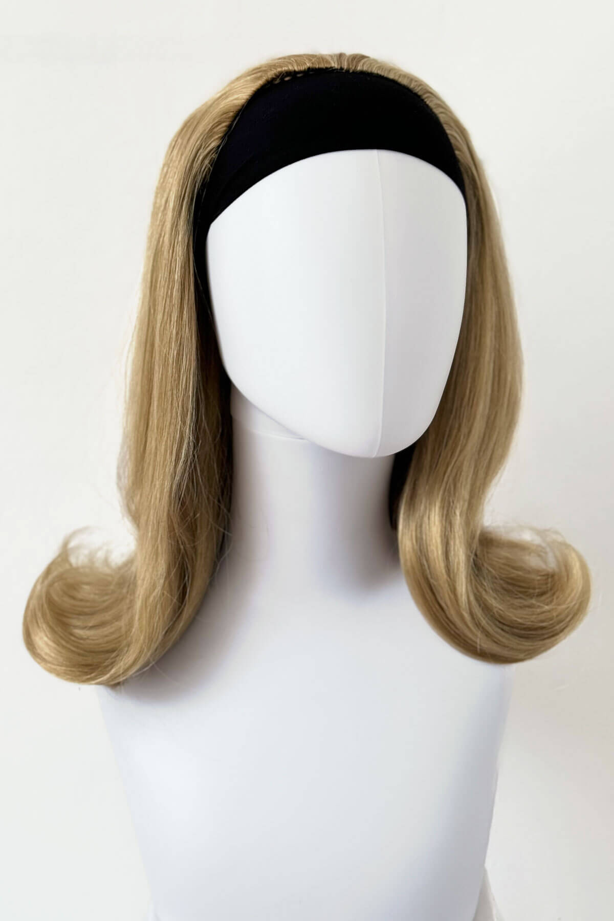 Blonde wig on a mannequin head with a white background. 1960s half wig hairpiece, flicked, hair flip: Philippa blonde 24H613