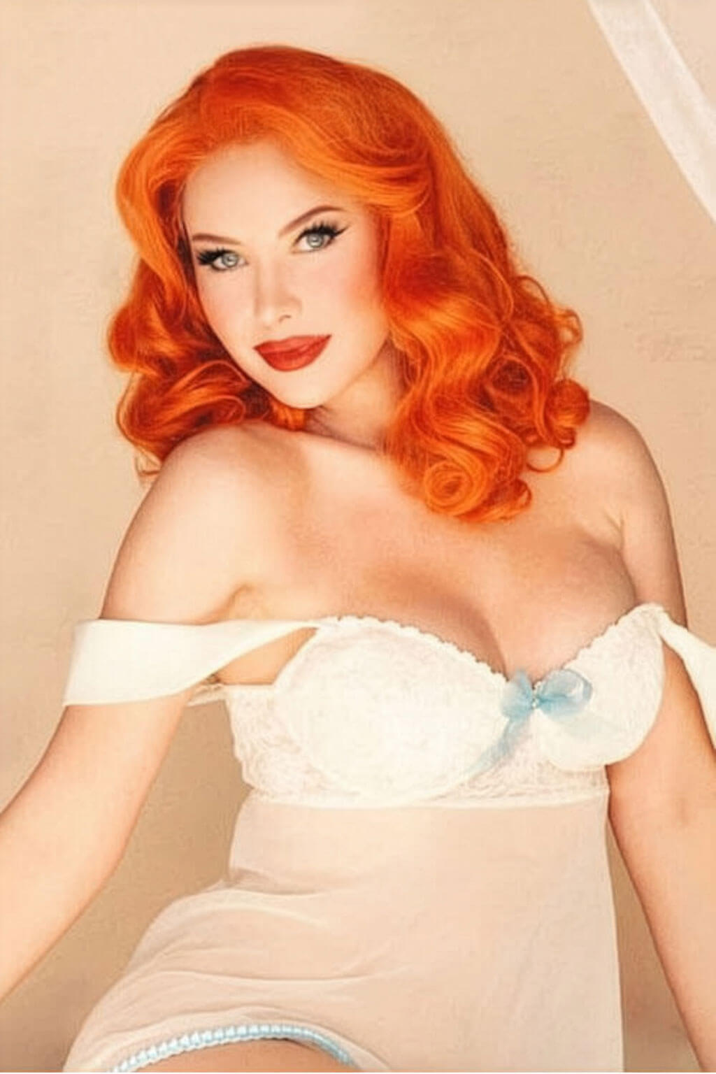 Woman with vibrant orange hair wearing a white lace top against a beige background. Ginger pinup lace front wig: Lula