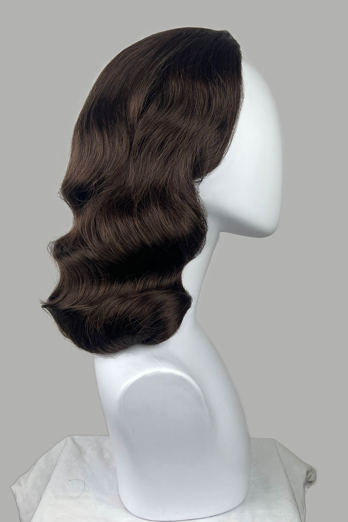Brown wig on a white mannequin head against a gray background. 1950s style half wig hairpiece with deep finger waves: Deborah brown 8