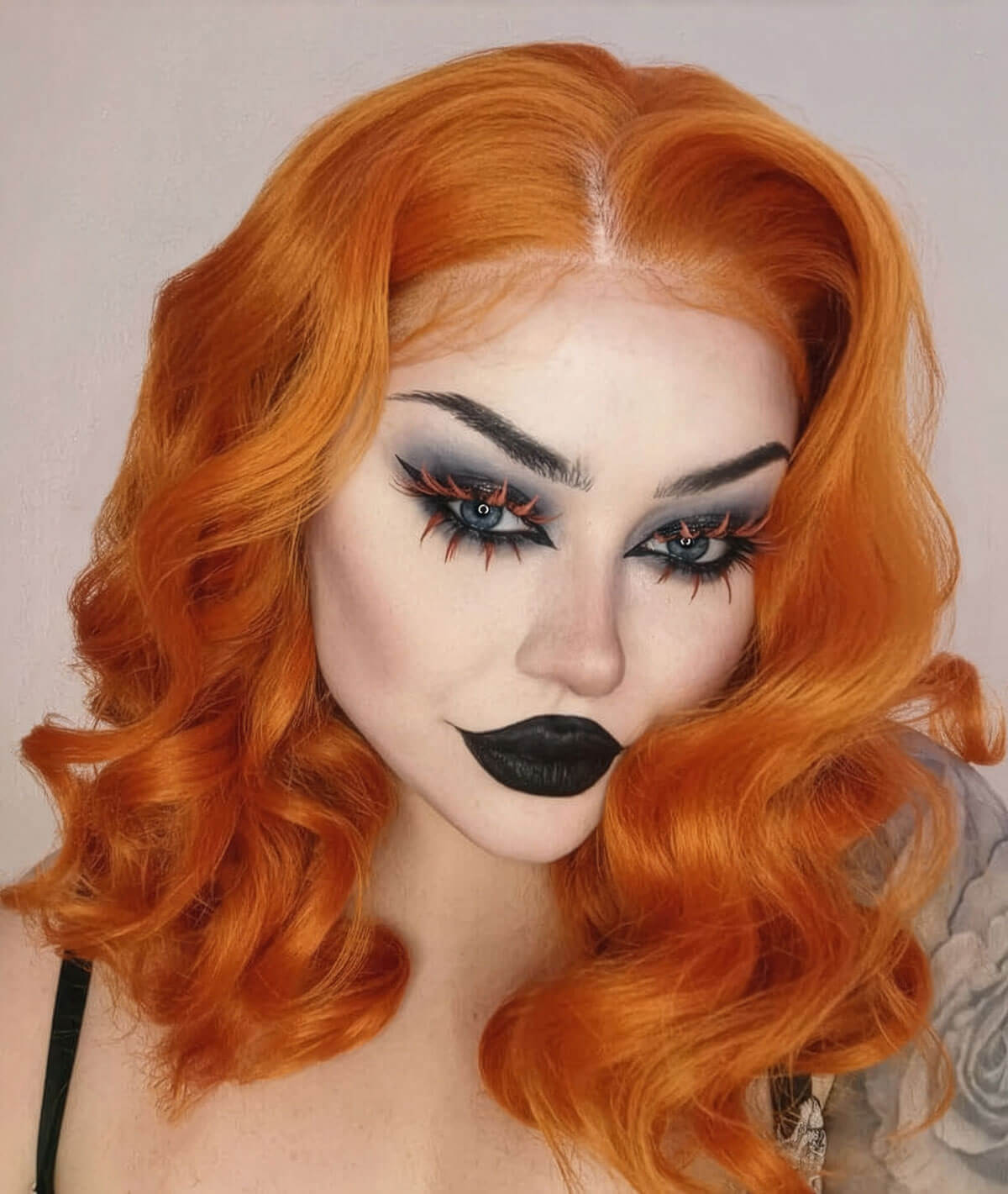 Person with vibrant orange hair and dramatic makeup on a neutral background. Ginger pinup lace front wig: Lula
