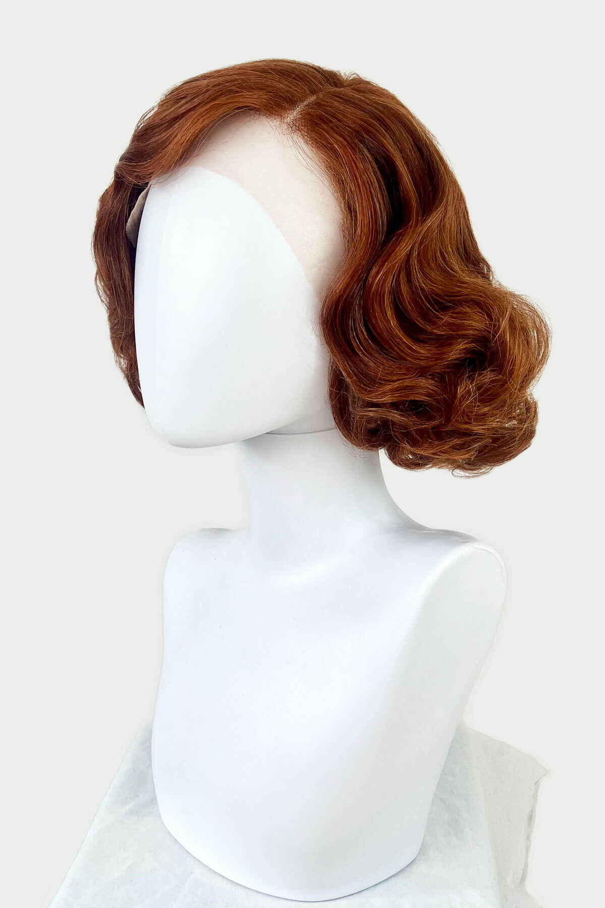 Brown wig on a white mannequin head against a white background. Auburn pinup wig, lace front, vintage style: Clementine