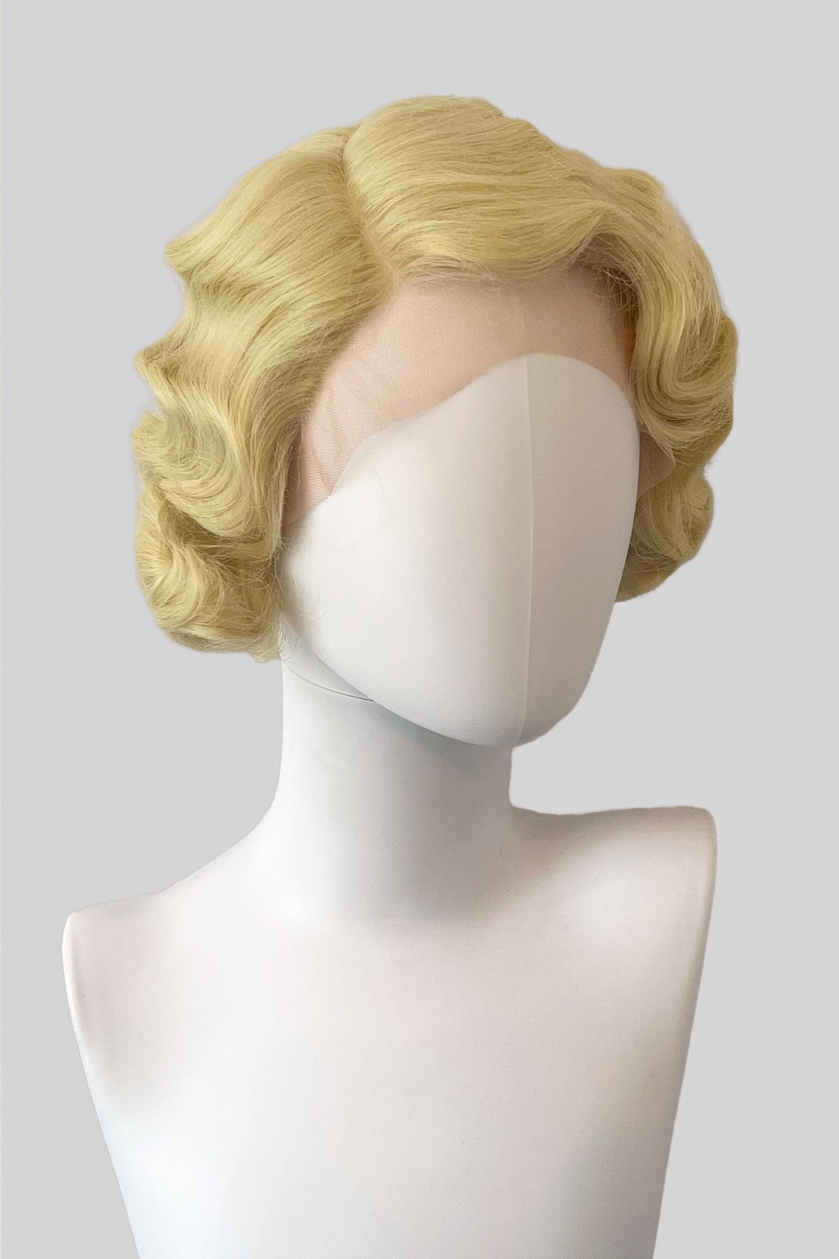 Blonde wig on a mannequin head against a plain background. Blonde pinup wig, lace front, vintage style: Odette blonde 613