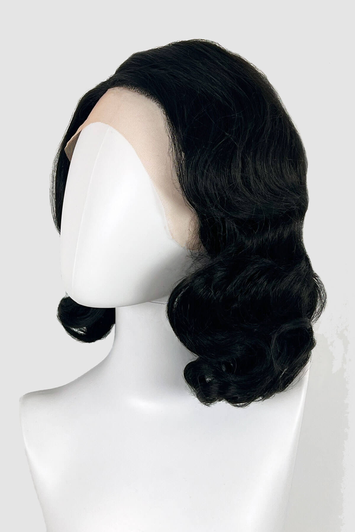 Black wig on a mannequin head against a white background. Black lacefront wig, pinup/vintage style, mid length with finger waves: Etta