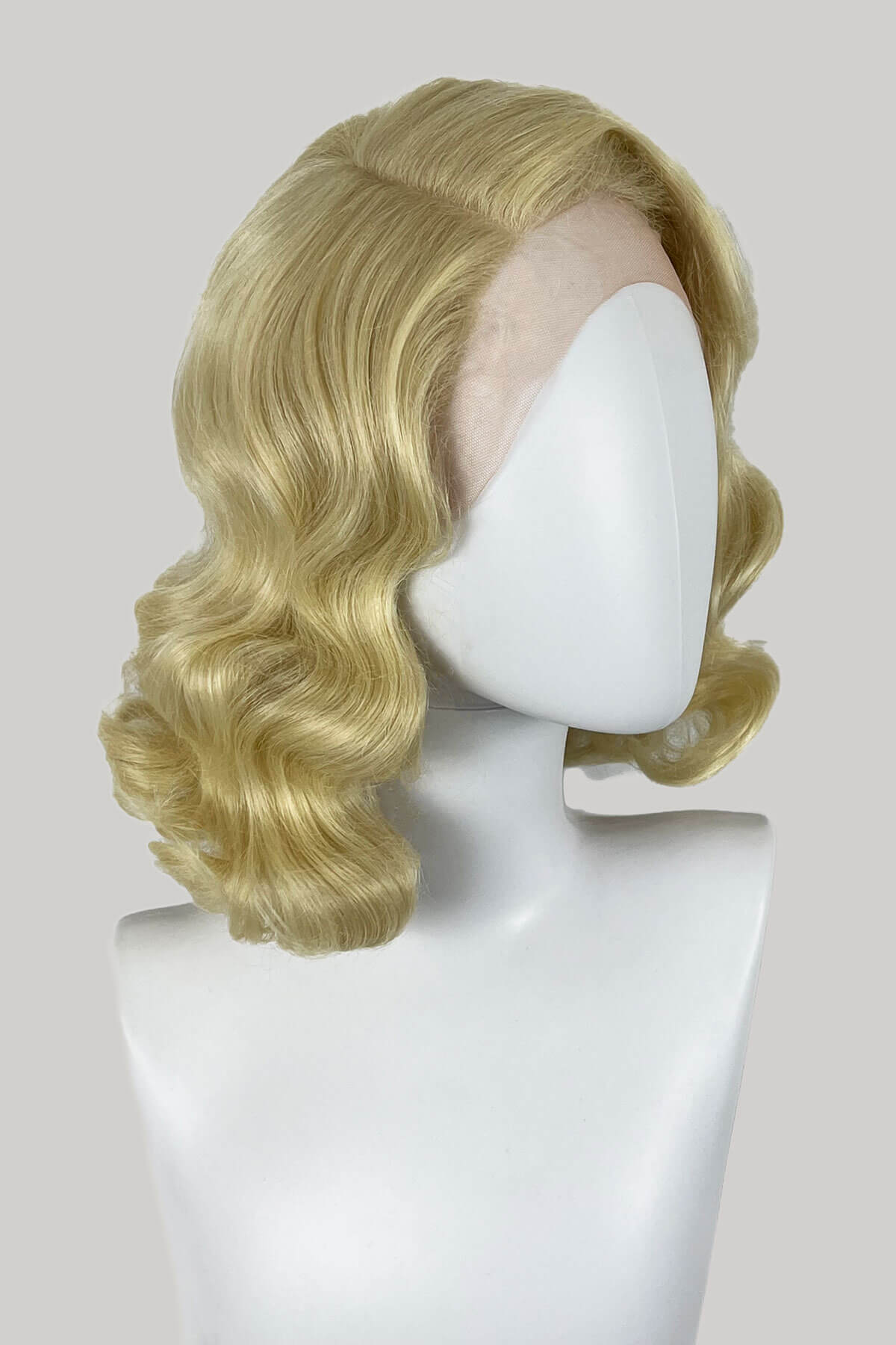Blonde wig on a mannequin head against a plain background. Blonde lace front wig, pinup/vintage style, mid length with finger waves: Lucinda creamy blonde 613