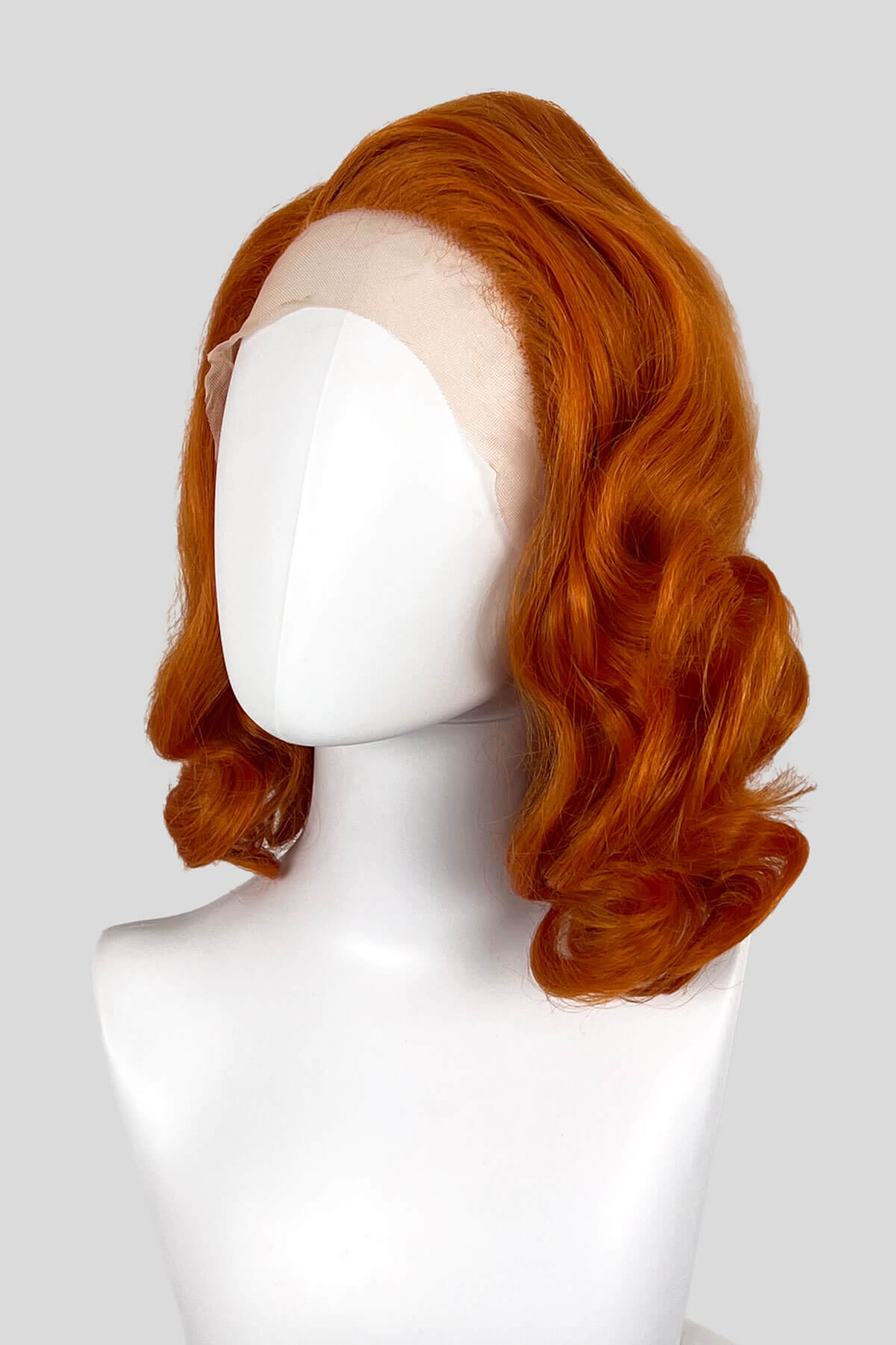 Red wig on a mannequin head against a white background. Ginger lace front wig, pinup/vintage style, mid length with finger waves: Flora