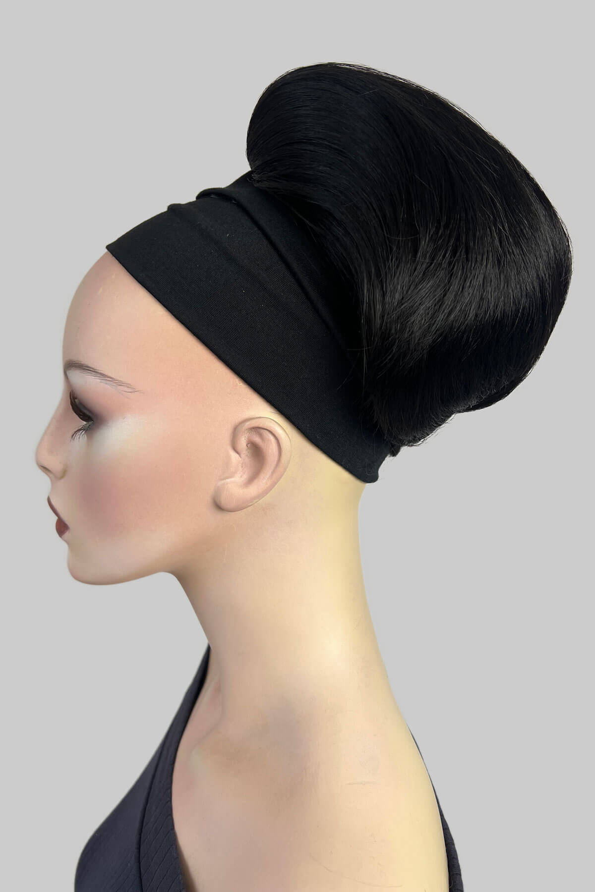 A mannequin wearing a green top and a beehive ponytail hairpiece in a soft blonde color. Short beehive ponytail hairpiece: Sherri Black 1B