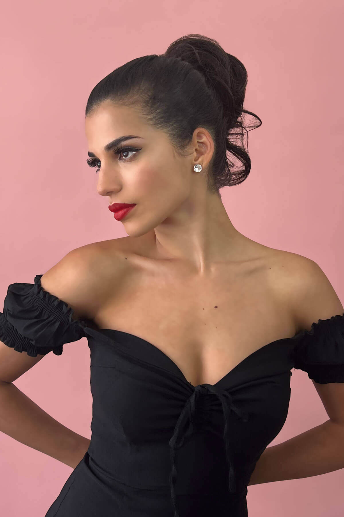 Woman in a black off-shoulder dress with red lipstick against a pink background. Short ponytail extension hairpiece, short with whisps: Leah